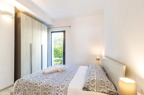 a white bedroom with a bed with a window at Alexander B&B in Tortolì