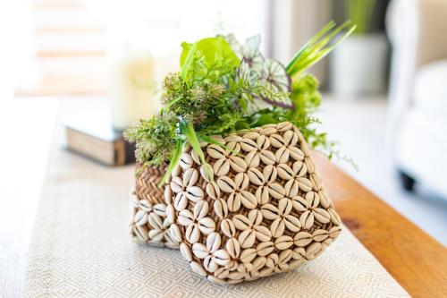 a vase with plants in it sitting on a table at ペンション ラナカイハウス沖縄 in Onna