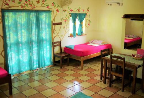 a room with two beds and a table and a table and chairs at Hospedaje Soma in Moyogalpa