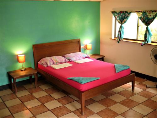 a bedroom with a red bed with two lamps at Hospedaje Soma in Moyogalpa