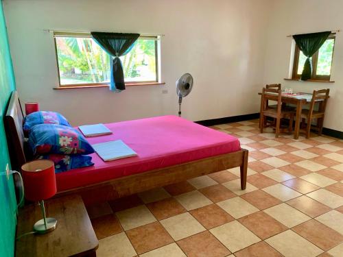 a bedroom with a red bed with a table at Hospedaje Soma Ometepe Hotel in Moyogalpa