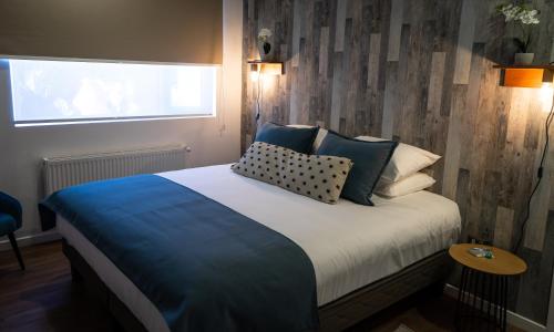 a bedroom with a bed with pillows and a window at Hotel Boutique Restaurant Kran Kreen in Punta Arenas