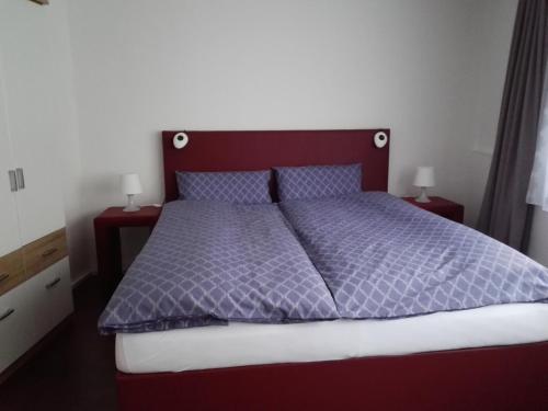 a bed with a purple comforter and two night stands at Ferienwohnung Delphin in Schönwald