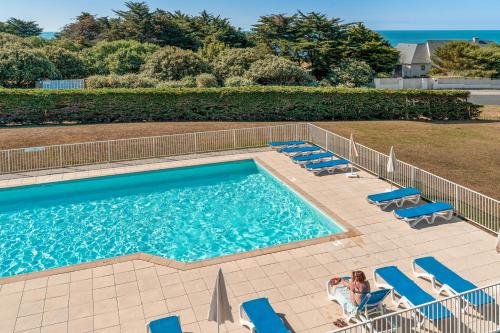 a swimming pool with blue chairs and people sitting in them at Résidence Pierre & Vacances Premium Le Domaine de Cramphore in Le Pouliguen