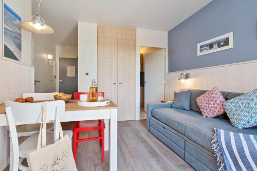 a living room with a blue couch and a table at Résidence Pierre & Vacances Premium Le Domaine de Cramphore in Le Pouliguen