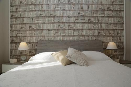 a bedroom with a white bed and a wall of books at CASA AZZURRA in Imperia
