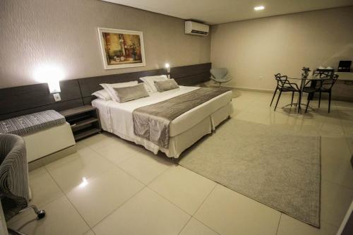 a bedroom with a bed and a table and chairs at Oscar Hotel Executive in Porto Velho