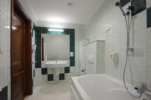 a bathroom with a bath tub and a sink at Manor Hotel in Olsztyn
