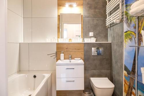 a bathroom with a sink toilet and a mirror at Apartament Yooka in Szczecin