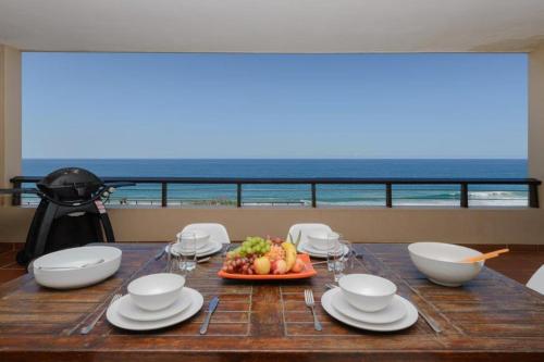 a table with a plate of fruit on it with a view of the ocean at Sunrise Beach View in Westbrook