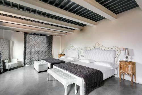 a white bedroom with two beds and a chair at Albergo Ristorante Madonnina in Cantello