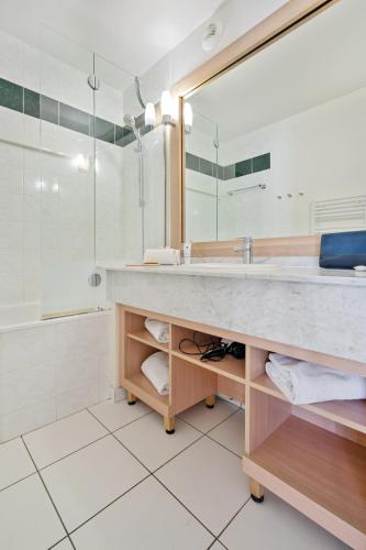 a bathroom with a sink and a large mirror at Résidence Pierre & Vacances Premium Le Domaine de Cramphore in Le Pouliguen