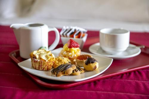 a plate of muffins and cups of coffee on a table at Santa Caterina Hotel & Bike in Chianciano Terme