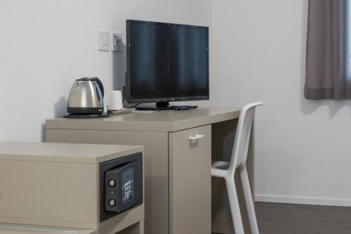 a desk with a tv and a computer on it at Hotel Cascina Fossata & Residence in Turin