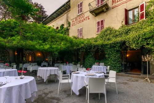 a restaurant with white tables and chairs in front of a building at Albergo Ristorante Madonnina in Cantello