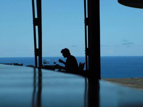 a man sitting in front of a window with a laptop at Explora en Rapa Nui - All Inclusive in Hanga Roa