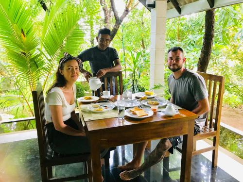 a group of people sitting around a wooden table at Bangalawa Resort in Habarana