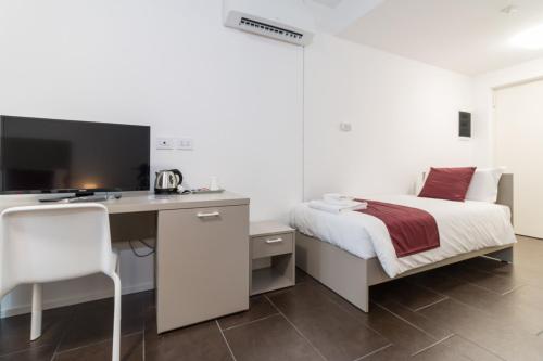 a bedroom with a bed and a desk with a computer at Hotel Cascina Fossata & Residence in Turin