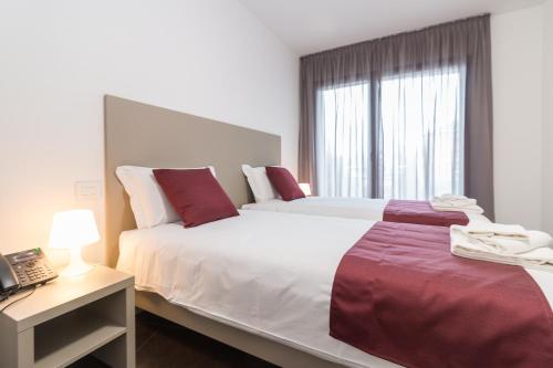 a bedroom with two beds and a desk with a laptop at Hotel Cascina Fossata & Residence in Turin