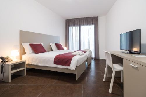 a bedroom with a bed and a desk with a computer at Hotel Cascina Fossata & Residence in Turin