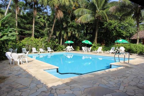 a swimming pool with chairs and umbrellas at Pousada Canto Verde in Boicucanga