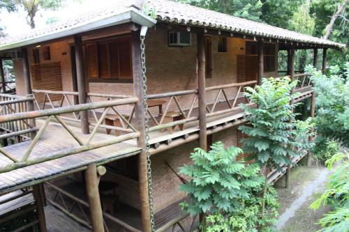 a wooden house with a porch and some trees at Pousada Canto Verde in Boicucanga