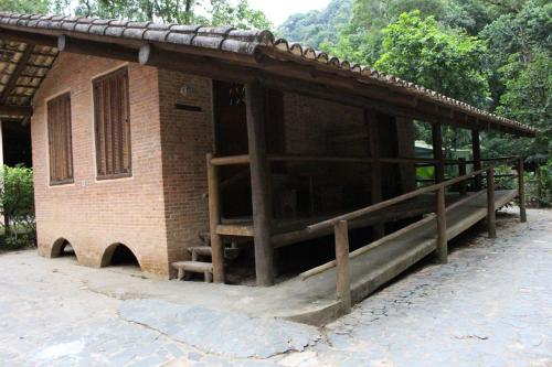 a small brick building with a porch and stairs at Pousada Canto Verde in Boicucanga
