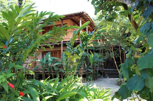 a wooden house is seen through the trees at Pousada Canto Verde in Boicucanga