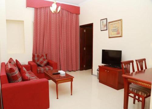 a living room with a red couch and a television at Al Sharq Hotels Suites in Sharjah
