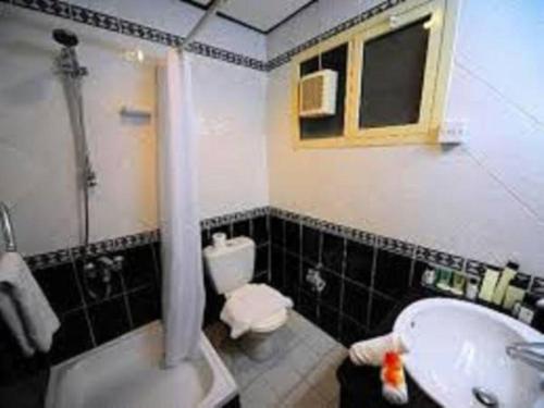 a bathroom with a sink and a toilet and a tub at Al Sharq Hotels Suites in Sharjah