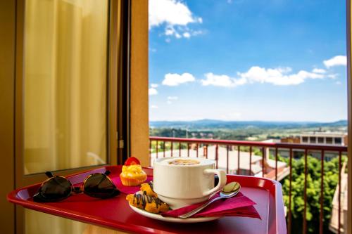 a tray with a cup of coffee and a plate of food at Santa Caterina Hotel & Bike in Chianciano Terme