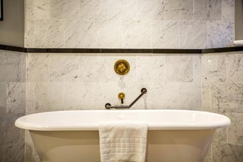a white bath tub in a bathroom with white tiles at voco Grand Central Glasgow by IHG in Glasgow