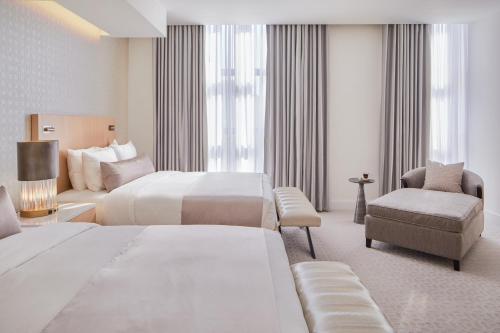 ein Hotelzimmer mit zwei Betten und einem Stuhl in der Unterkunft The Kindler Hotel in Lincoln