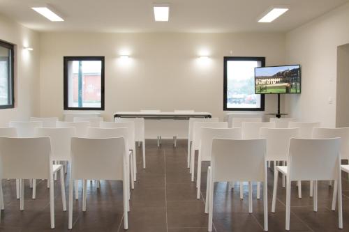 a room with white chairs and a flat screen tv at Hotel Cascina Fossata & Residence in Turin
