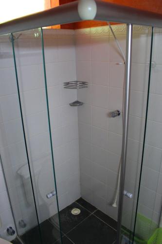 a shower in a bathroom with white tiles at Pousada Canto Verde in Boicucanga