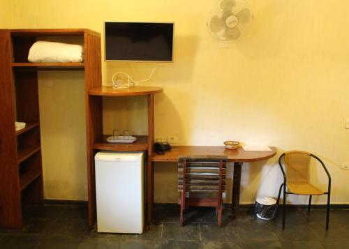 a room with a desk and a table and a television at Pousada Canto Verde in Boicucanga