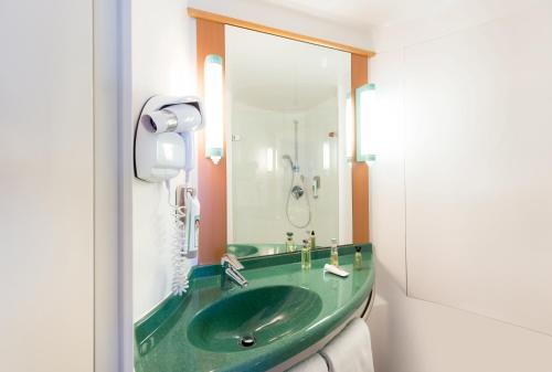 ein Badezimmer mit einem grünen Waschbecken und einem Spiegel in der Unterkunft ibis Luxembourg Sud in Livange