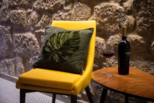 a yellow chair with a bottle of wine and a glass at Casa Jardim in Porto