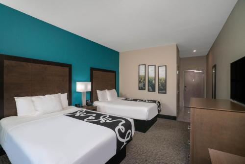 a hotel room with two beds and a flat screen tv at La Quinta by Wyndham West Memphis in West Memphis