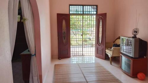 a living room with two doors and a tv at Homestay Zahra Sri Bayu in Kampong Dalam Ru