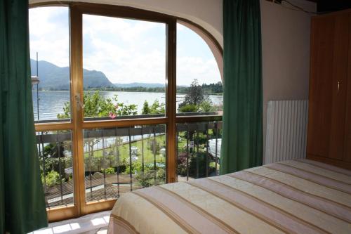 een slaapkamer met een groot raam met uitzicht op het water bij Albergo Ristorante Punta Dell'Est in Clusane sul Lago