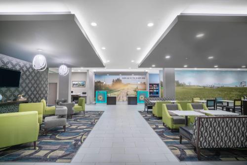 a restaurant with green chairs and tables and a large screen at La Quinta by Wyndham West Memphis in West Memphis