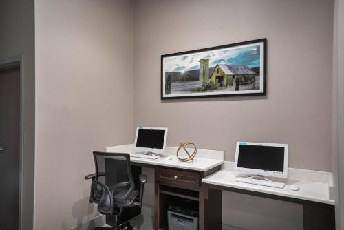 two computers on a desk with a picture on the wall at La Quinta by Wyndham West Memphis in West Memphis
