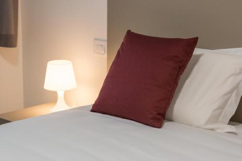 a red pillow sitting on top of a bed with a lamp at Hotel Cascina Fossata & Residence in Turin