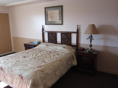 a bedroom with a bed and two night stands and a lamp at Traveller's Inn in Dawson Creek