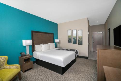 a hotel room with a bed and a chair at La Quinta by Wyndham West Memphis in West Memphis