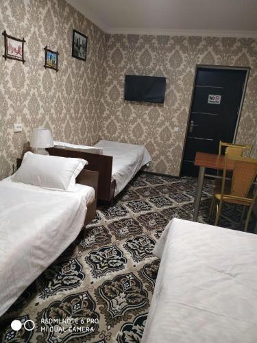a hotel room with three beds and a table at Imran&Bek in Samarkand