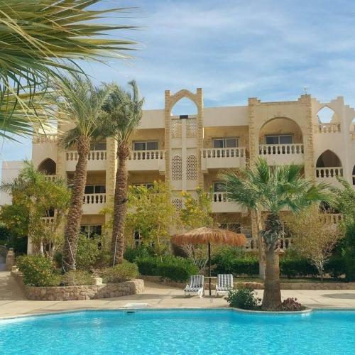 a large building with palm trees and a swimming pool at One- bedroom apartment S3 in Vip Zone Sunny Lakes in Sharm El Sheikh