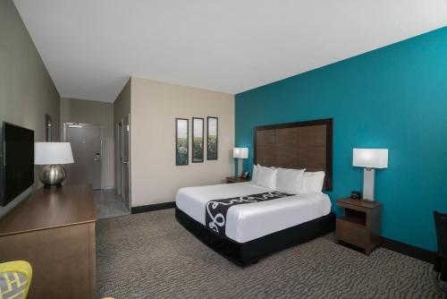 a bedroom with a large bed and a blue wall at La Quinta by Wyndham West Memphis in West Memphis