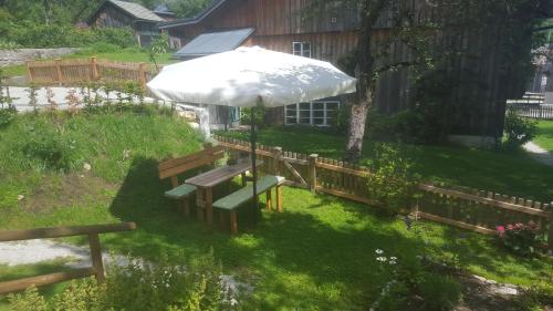 a park bench with an umbrella in a yard at Haus Familie Säckl in Altaussee